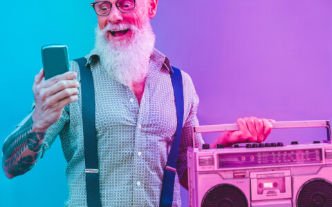 Senior hipster man using smartphone app for creating playlist – Trendy tattoo guy having fun with mobile phone technology – Tech and joyful elderly lifestyle concept – Radial purple and blue filter
