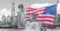 Statue of Liberty with a large american flag and New York skyline in the background